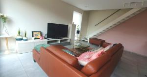 een woonkamer met een bruine leren bank en een trap bij Mooi vakantiehuis tussen Breda, Antwerpen, Gent & Hasselt in Antwerpen
