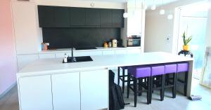 een keuken met witte kasten en paarse barkrukken bij Mooi vakantiehuis tussen Breda, Antwerpen, Gent & Hasselt in Antwerpen