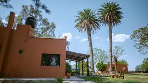 a building with two palm trees in a park at Inti, hospedaje de campo. in Arrecifes