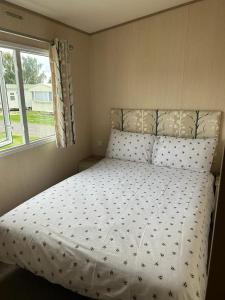 a bedroom with a bed with a white comforter and a window at Ralph’s Retreat in Cottam