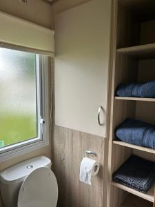 a bathroom with a toilet and a window and towels at Ralph’s Retreat in Cottam