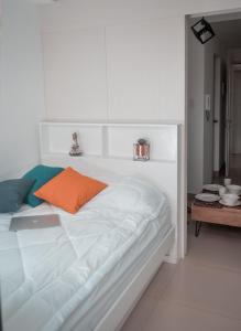 a white bed with an orange pillow on it at Coolspace @ SMDC Wind Residence Budget, WIFI, NETFLIX in Tagaytay