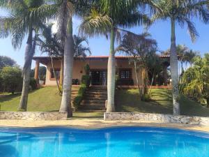 a house with palm trees in front of a swimming pool at Chácara Rancho da Coruja in Itu