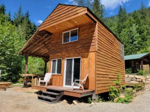 a tiny house with two chairs and a table at Noah's Ark Campground in Revelstoke