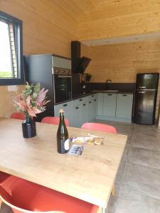 a kitchen with a wooden table with a bottle of wine at Le Chalet de St Vigor in Saint-Vigor-le-Grand