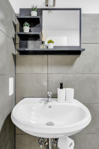 La salle de bains est pourvue d'un lavabo blanc et d'un miroir. dans l'établissement 2 Zimmer Apartment,4 Betten am Sbahnhof Köpenick,vollmöbliert, à Berlin
