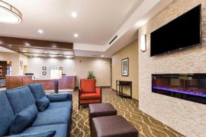 a living room with a blue couch and a flat screen tv at Comfort Suites Greenville South in Piedmont