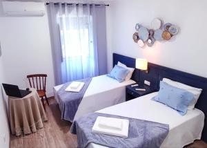 una camera d'albergo con due letti e una sedia di Casa da Floresta a Covilhã