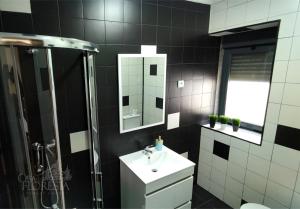 a black and white bathroom with a sink and a shower at Casa da Floresta in Covilhã