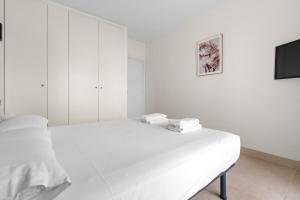 um quarto branco com uma cama e uma televisão em Apartamento WELCS EMP 093 con vistas al Canal em Empuriabrava