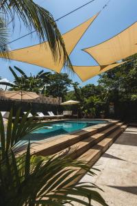 ein Schwimmbad mit gelbem Regenschirm darüber in der Unterkunft Hotel Michanti in El Zonte