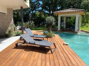 zwei Liegestühle und ein Tisch neben einem Swimmingpool in der Unterkunft Villa d’exception Montpellier in Saint-Jean-de-Védas