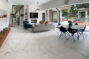 ein Wohnzimmer mit weißem Marmorboden und einem Tisch und Stühlen in der Unterkunft Villa d’exception Montpellier in Saint-Jean-de-Védas