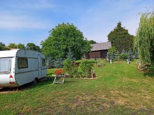 a camper parked in a field next to a garden at Kwatera u Stasia in Szczebrzeszyn