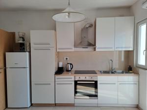 a kitchen with white cabinets and a white refrigerator at Yulia Apartman in Pula