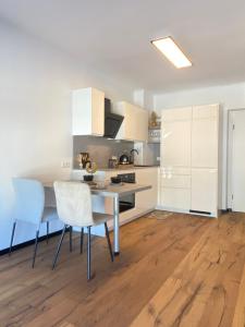 a kitchen with white cabinets and a table and chairs at BaMo Studio - city living downtown in Klagenfurt