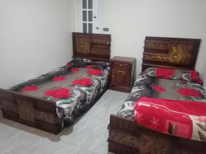 two beds in a bedroom with red sheets at شقة مصيفية بدمياط الجديدة قريبة من الشاطئ والخدمات in Dumyāţ al Jadīdah