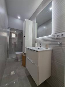 La salle de bains blanche est pourvue d'un lavabo et de toilettes. dans l'établissement Nueva Almería beach & chill, à Almería