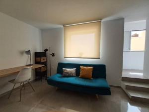 - un salon avec un canapé bleu et une table dans l'établissement Nueva Almería beach & chill, à Almería