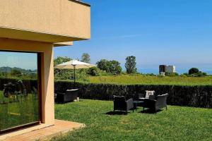 a patio with chairs and an umbrella in the grass at Seagarden Villa Resort / Villa Dimar 2C in Lozenets