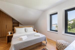 a bedroom with a bed and two windows at Villa B with Old town & sea view in Dubrovnik