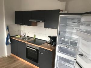a kitchen with black cabinets and an empty refrigerator at Erholungszeit - Mein kleines Paradies in Bad Kreuznach