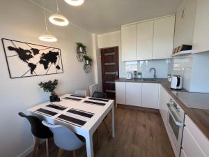 kuchnia z białym stołem i krzesłami w obiekcie Apartament z widokiem na morze w mieście Gdynia