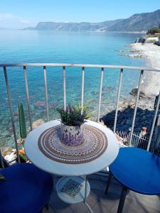 una mesa y sillas en un balcón con vistas al océano en Rosa dei venti, en Scilla
