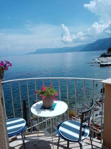 una mesa y sillas en un balcón con vistas al agua en Rosa dei venti, en Scilla
