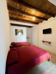 a bedroom with a red bed and a flat screen tv at COLIBRI GUEST HOUSE in Puerto López