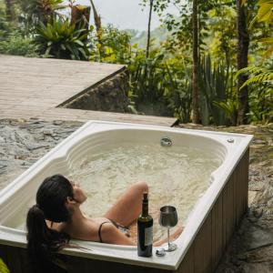 a woman sitting in a bath tub with a bottle of wine at Terramia Estate in Minca