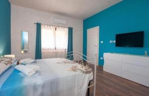 a blue bedroom with a bed and a television at Da Claudietto in San Teodoro