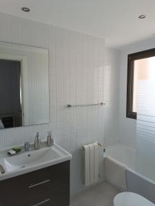 uma casa de banho com um lavatório, uma banheira e um espelho. em Apartamento Holydais Monica em Múrcia