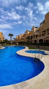 a large pool with blue water in front of buildings at ÁTICO TERESA BORA PALM, PISCINA PRIVADA CLIMATIZABLE 250m playa in Vera