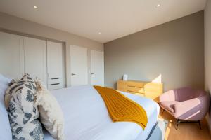 a bedroom with a white bed and a pink chair at Capitalia - Apartments - Santa Fe in Mexico City