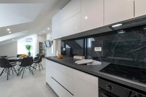 a kitchen with white cabinets and a black counter top at Apartment Meri in Dubrovnik