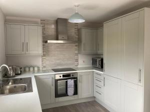 a white kitchen with white cabinets and a sink at Willow Tree Cottage in Ballycastle