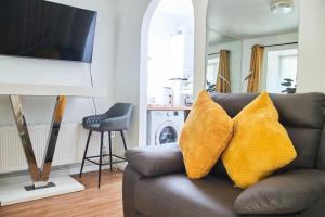 a living room with a couch with two yellow pillows at Superb One bedroom house in Thamesmead