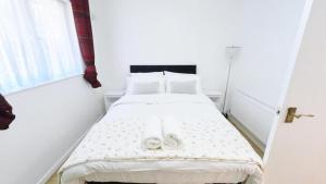 a white bed in a white room with a window at Superb One bedroom house in Thamesmead