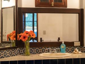 a bathroom sink with a vase of flowers and a mirror at Casita Del Escritor in Antigua Guatemala