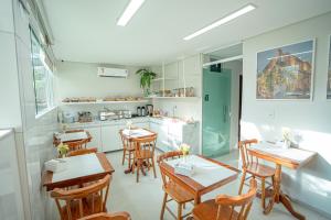 a dining room with tables and chairs and a kitchen at Pousada Antonella in Maragogi