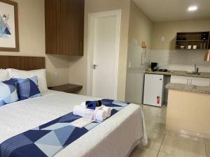 a bedroom with a blue and white bed and a kitchen at Areias de Tucuns Lofts e Apartamentos in Búzios