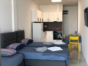 a bedroom with two beds with blue sheets and a kitchen at Aliara Dilara Beach Apartments in Pomorie