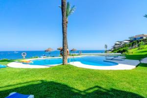 a swimming pool with a palm tree next to the ocean at La Cala on the beach sunsets view. in La Cala de Mijas