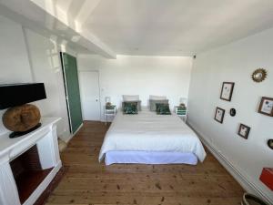 a white bedroom with a bed and a tv at Location de maison Au fil de l O la Bouille in La Bouille