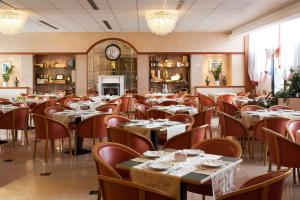 un restaurante con mesas y sillas y un reloj en Best Western Hotel Leonardo da Vinci, en Erba