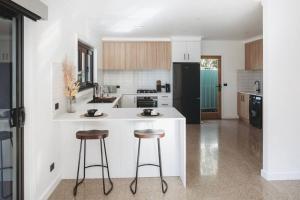 a kitchen with two bar stools and a white counter at Leafy Retreat - Benalla in Benalla