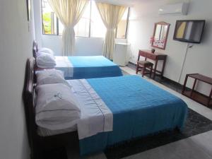 um quarto com duas camas e uma televisão em HOTEL DINASTIA REAL NEIVA em Neiva