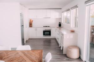 a kitchen with white cabinets and a wooden floor at The Vine House - Benalla in Benalla