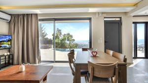 a dining room with a table and a large window at Ecstasy Luxury Villas in Apolpaina